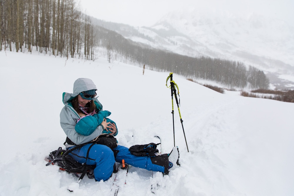 Woman holding baby in snow with ski boots on in Crested Butte Colorado