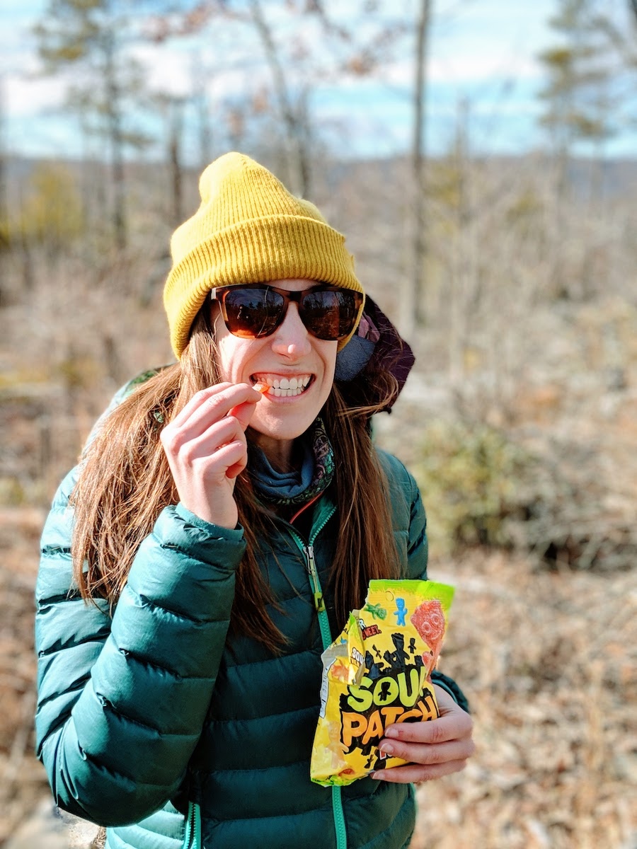 A woman eating Sour Patch Kids in the woods