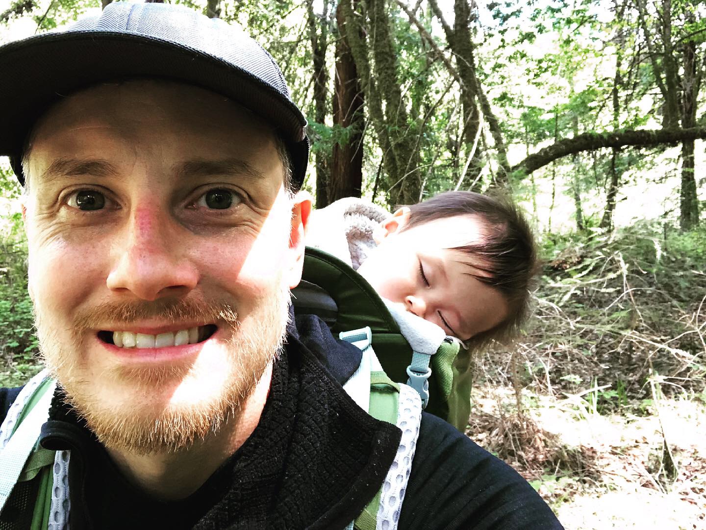 Man in woods with baby sleeping in backpack