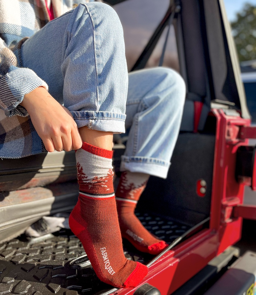 Woman putting on a sock sitting in a red jeep
