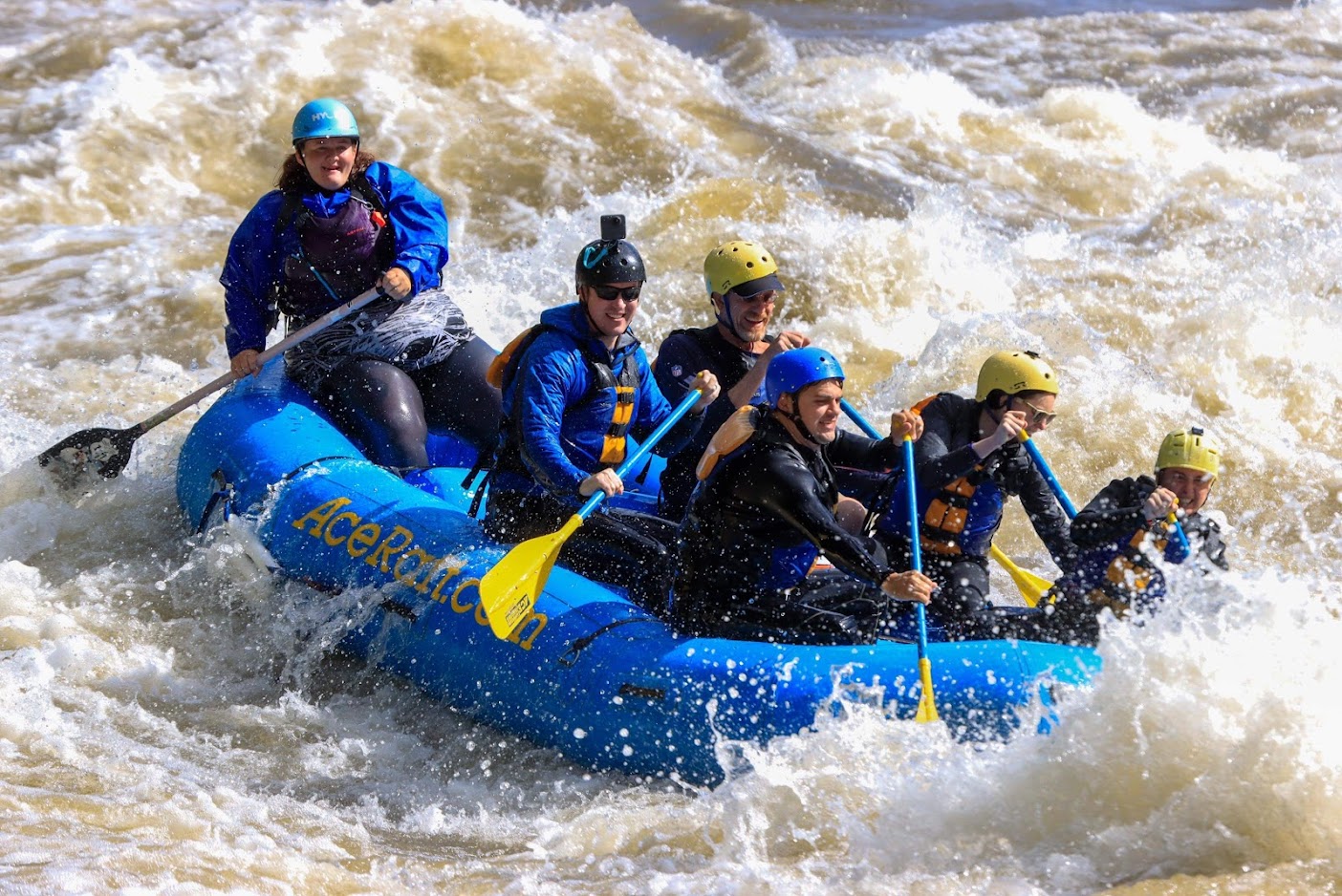 People whitewater rafting on a blue raft that says AceRaft.com