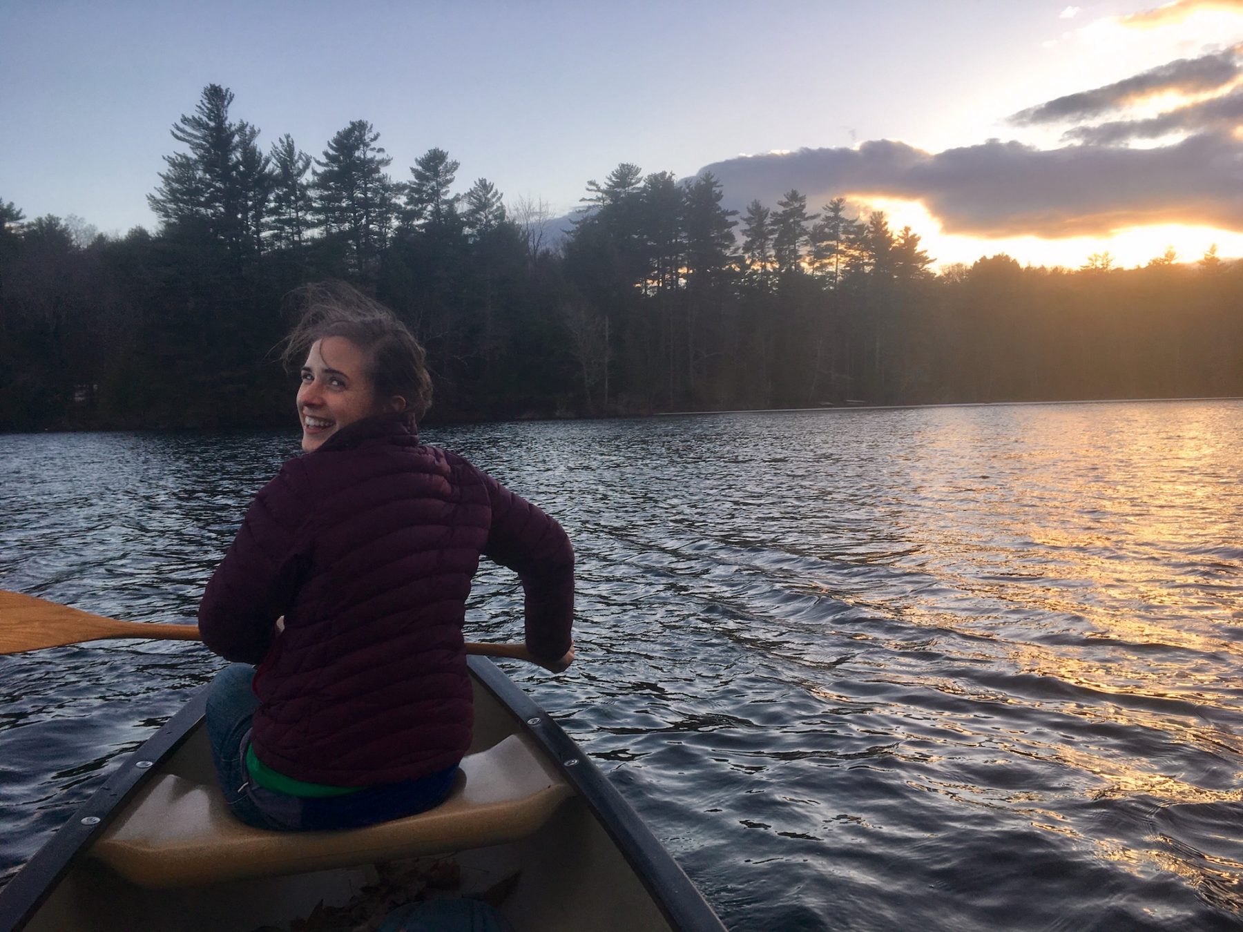Woman paddling a canoe on a lake
