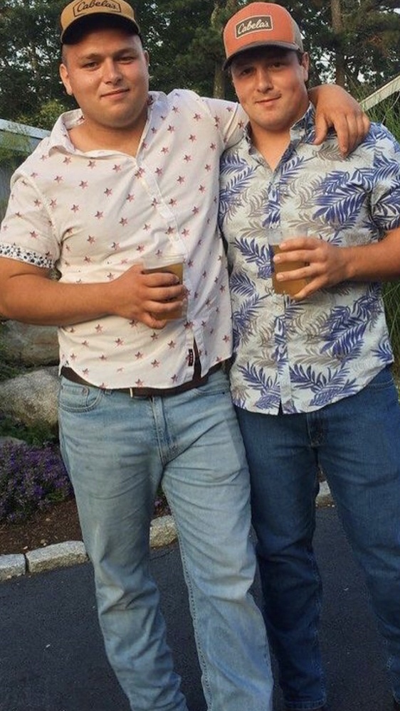 Two guys standing with the arms around each other and a beer in their hands