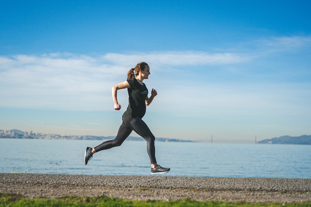 Tina Muir running on a beach with the Golden Gate bridge behind her
