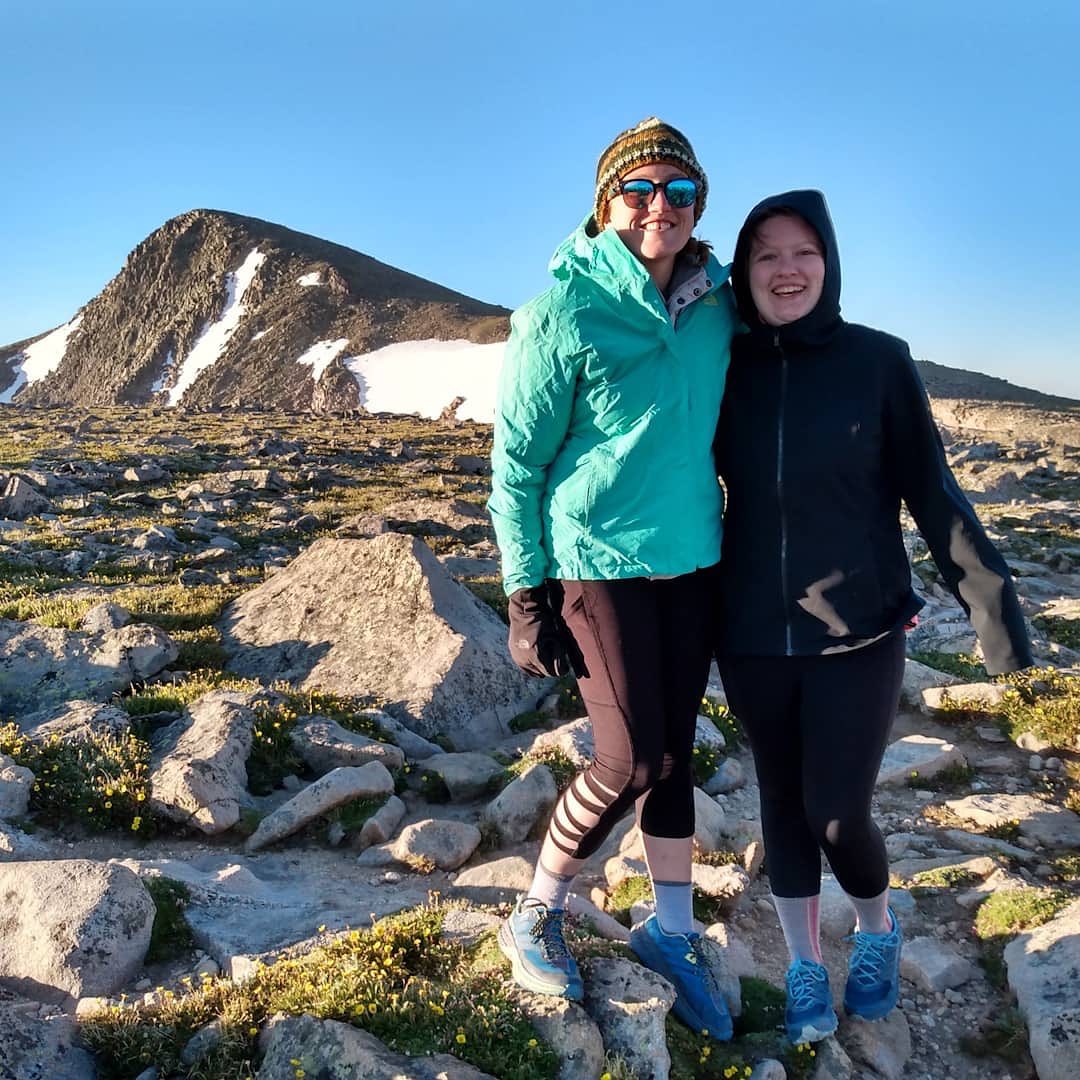 Two women posing in a rock field atop a mountain. 
