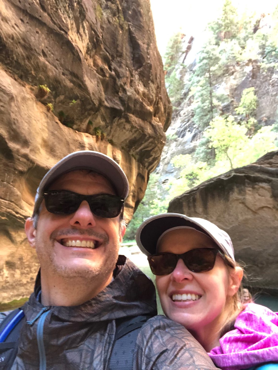 Two people posing for a picture on a hike in the middle of two large rocks