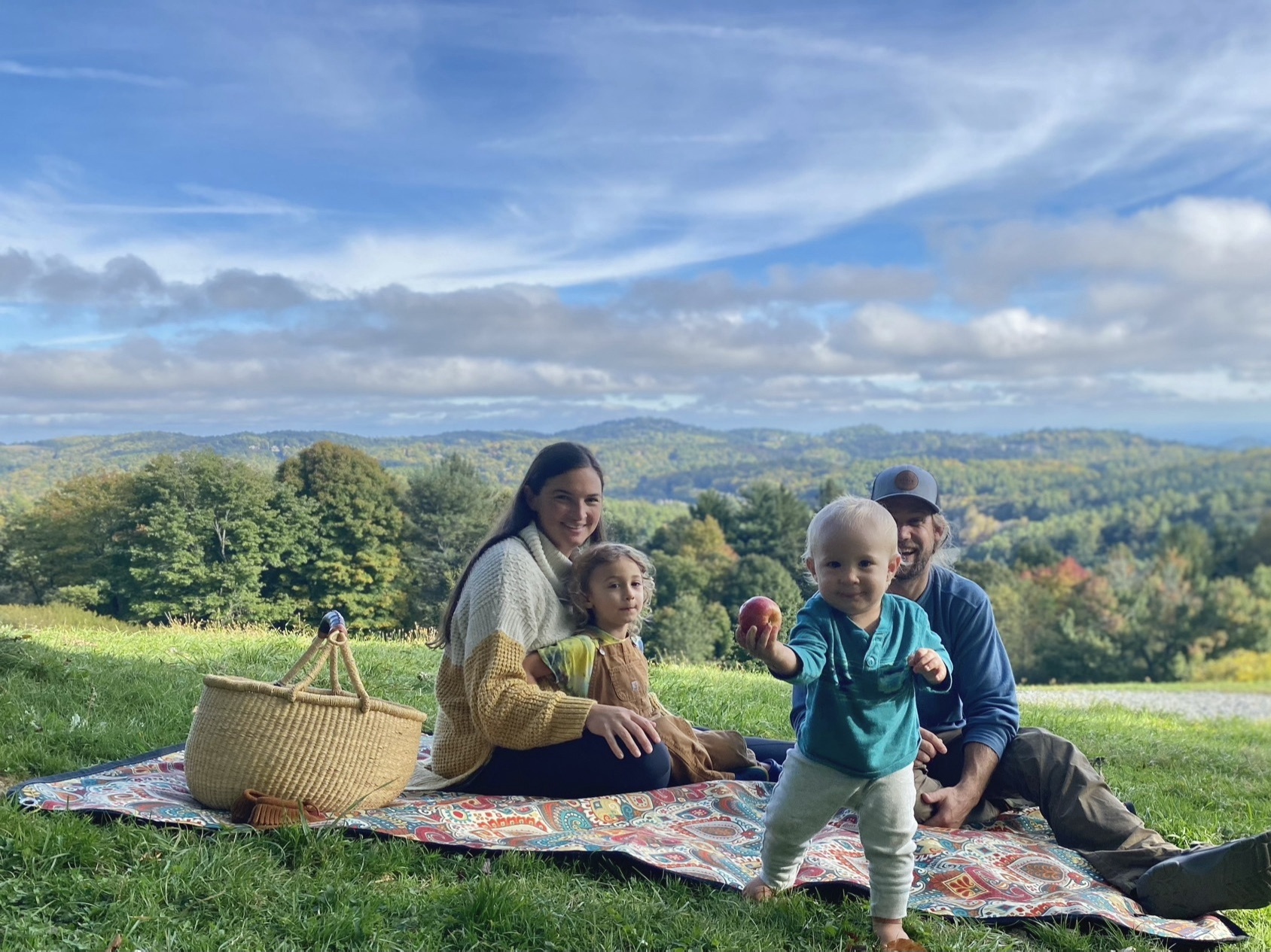 Family sitting on a Tarpestry blanket having a picnic to #optoutside for the day. 